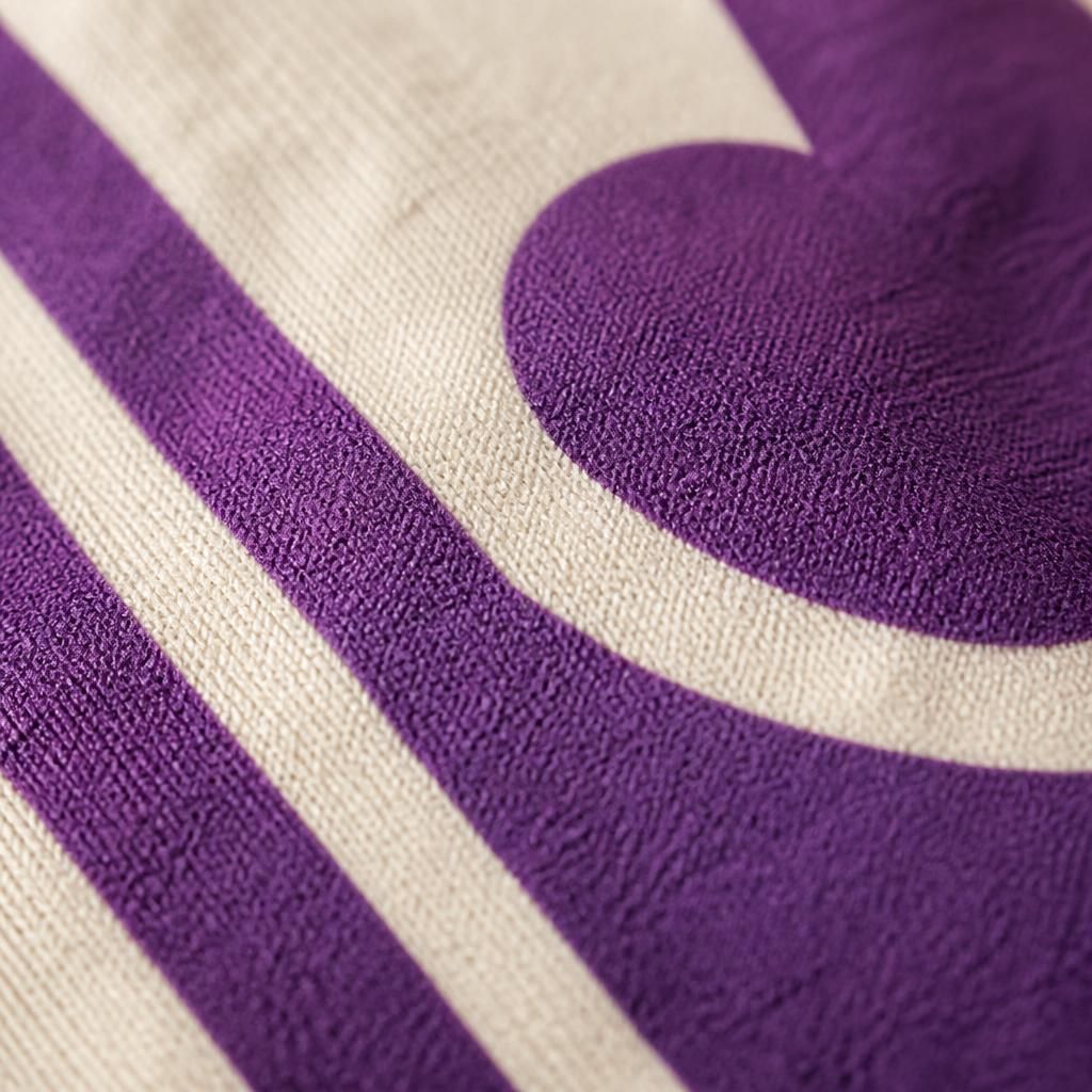 Close-up of a raised purple screen print on cream cotton showing the fabric weave